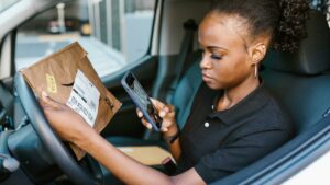 Woman doing gig work scanning Amazon package in car