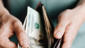 US bills in leather wallet depicting cost savings from background checks