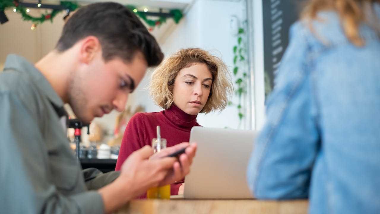 Worried woman performing online background check on laptop while someone else on phone