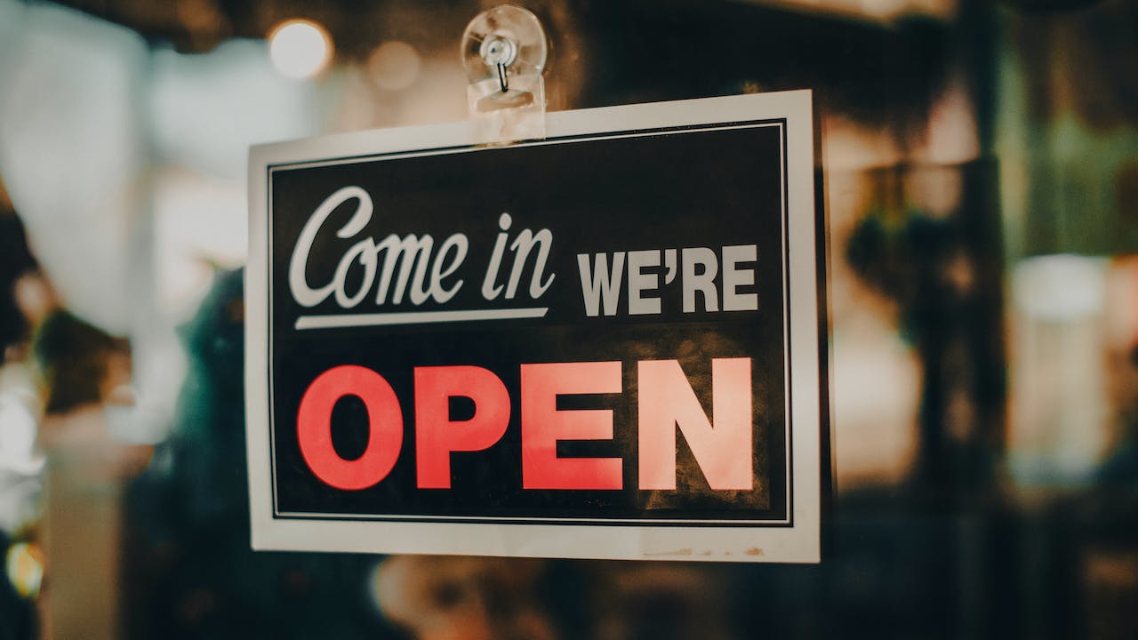 Open for business sign on store depicting how owners can protect their business assets with background checks