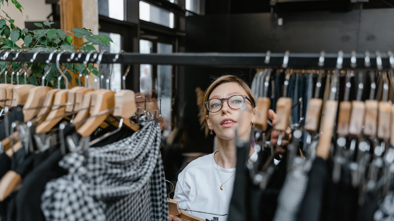 Female retail employee at clothing rack showing in-person retail hiring trends for 2023