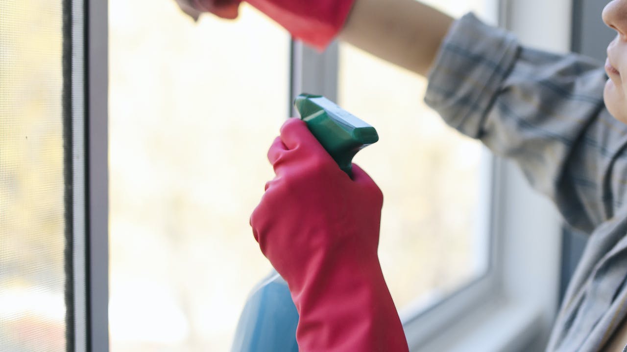 Cleaner washing window in a home after undergoing best background check for cleaning business