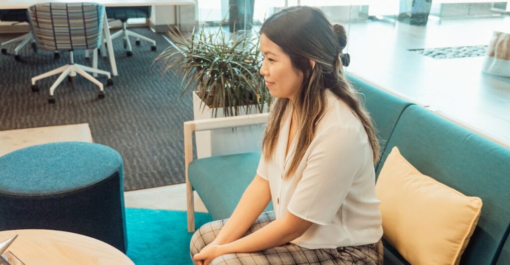 Female candidate waiting on couch in office for job interview to use tips for addressing a criminal record in an interview