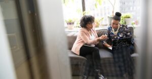 Staffing agency owner and colleague sitting on couch using best background checks for staffing agencies