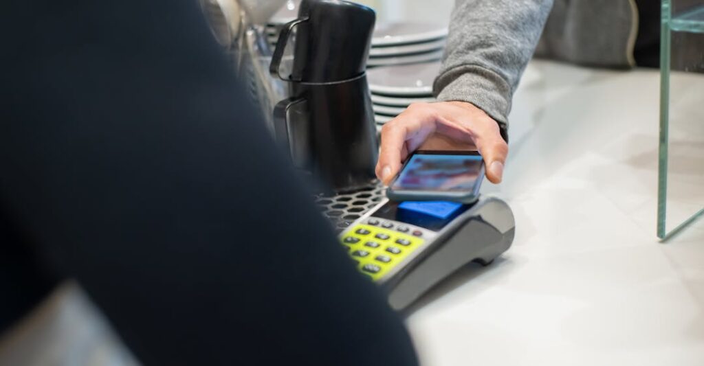 Individual using payment method on smartphone to pay at coffee shop to represent digital trust and ease of digital trust for background screening