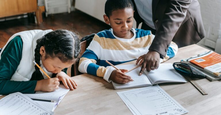 Primary school educator with teacher background check helping student with worksheet at desk