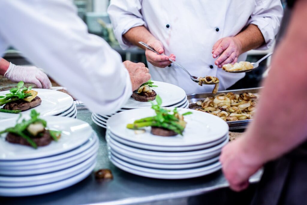Chefs preparing plated meal in kitchen representing hotel hiring in 2025 .jpg